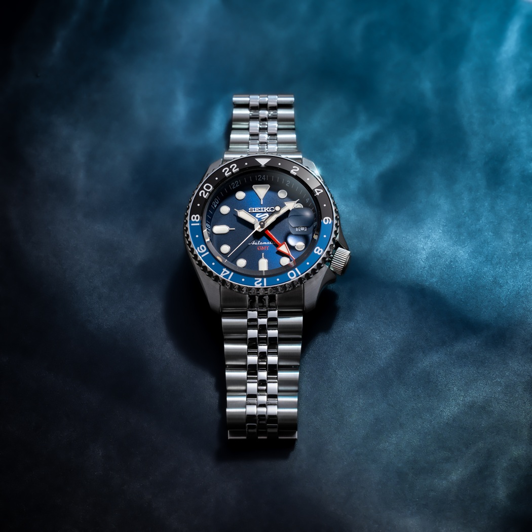 Đồng hồ Seiko 5 Sports SSK003K1 màu xanh dương, kim GMT, dây kim loại, đặt dưới nền xanh dương đen