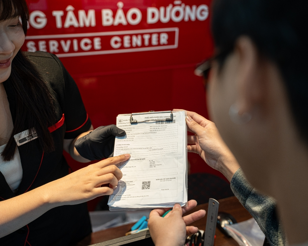 Nhân viên tư vấn tại đại lý đang giải thích chi tiết bảng quyền lợi bảo hành cho khách hàng.