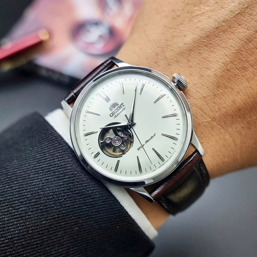 Đồng hồ Orient Bambino Open Heart mặt trắng đeo trên cổ tay nam mặc sơ mi công sở
