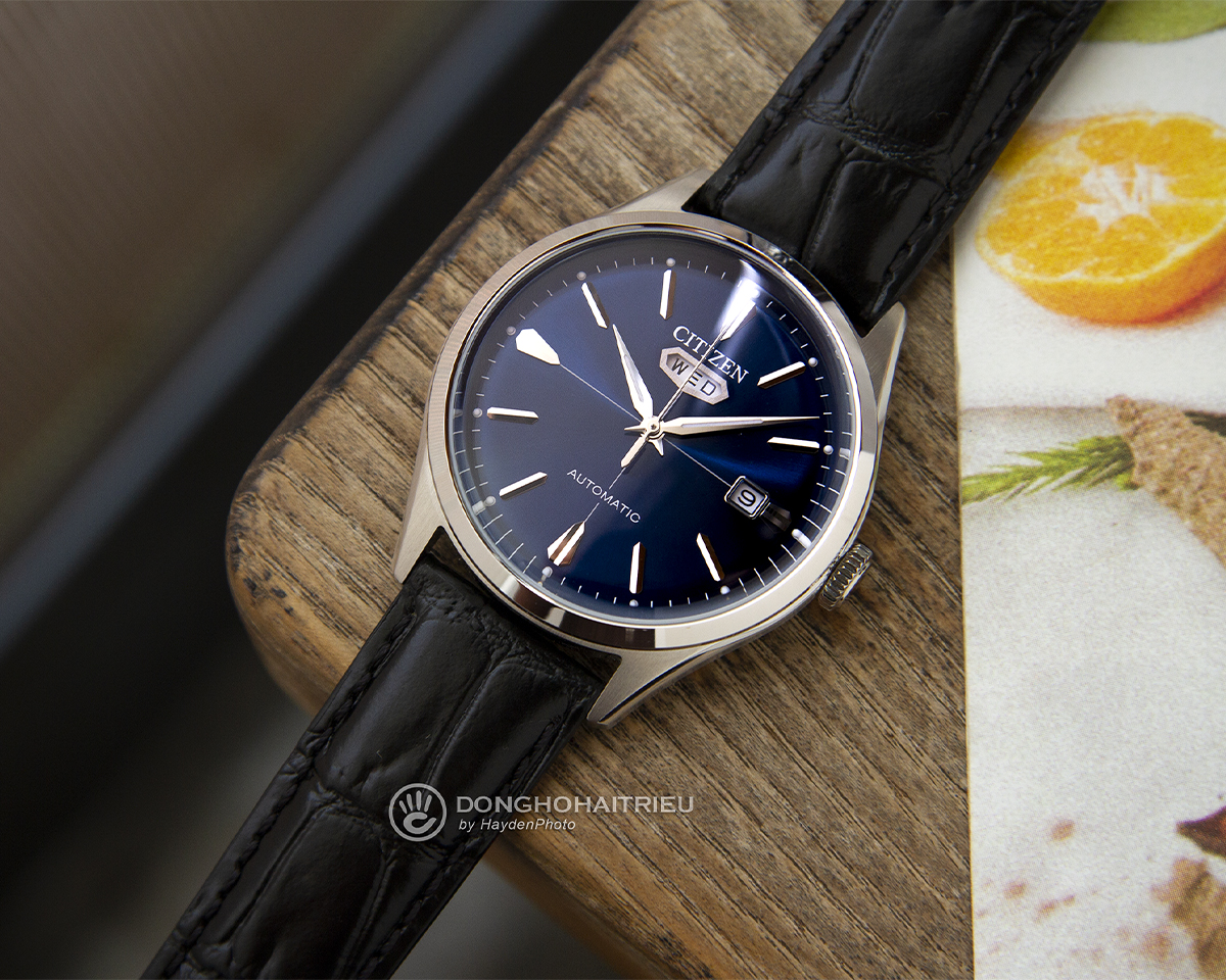 Đồng hồ Citizen C7 NH8390-20L sở hữu mặt số xanh dương, dây da đen vân cá sấu và thiết kế lịch thứ hình thất giác đặc trưng tại góc 12 giờ.
