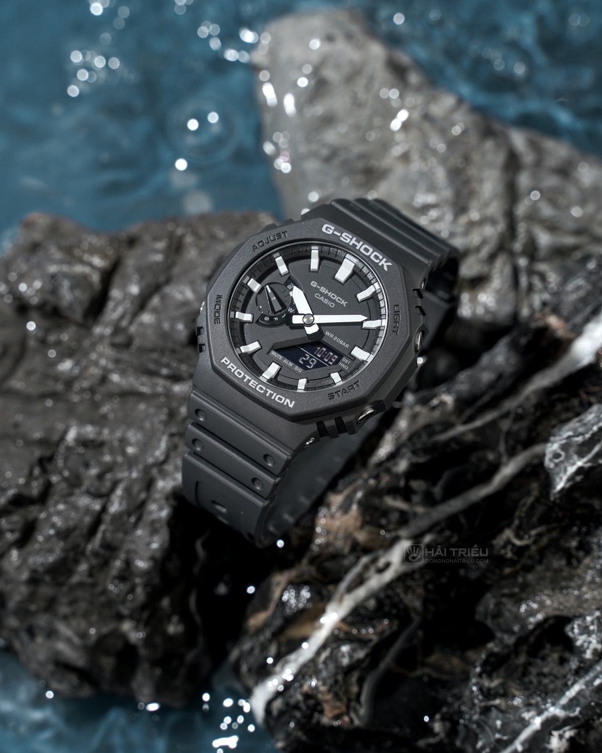 Đồng hồ G-Shock GA-2100-1ADR dáng bát giác đặt trên đá ướt gần nước.