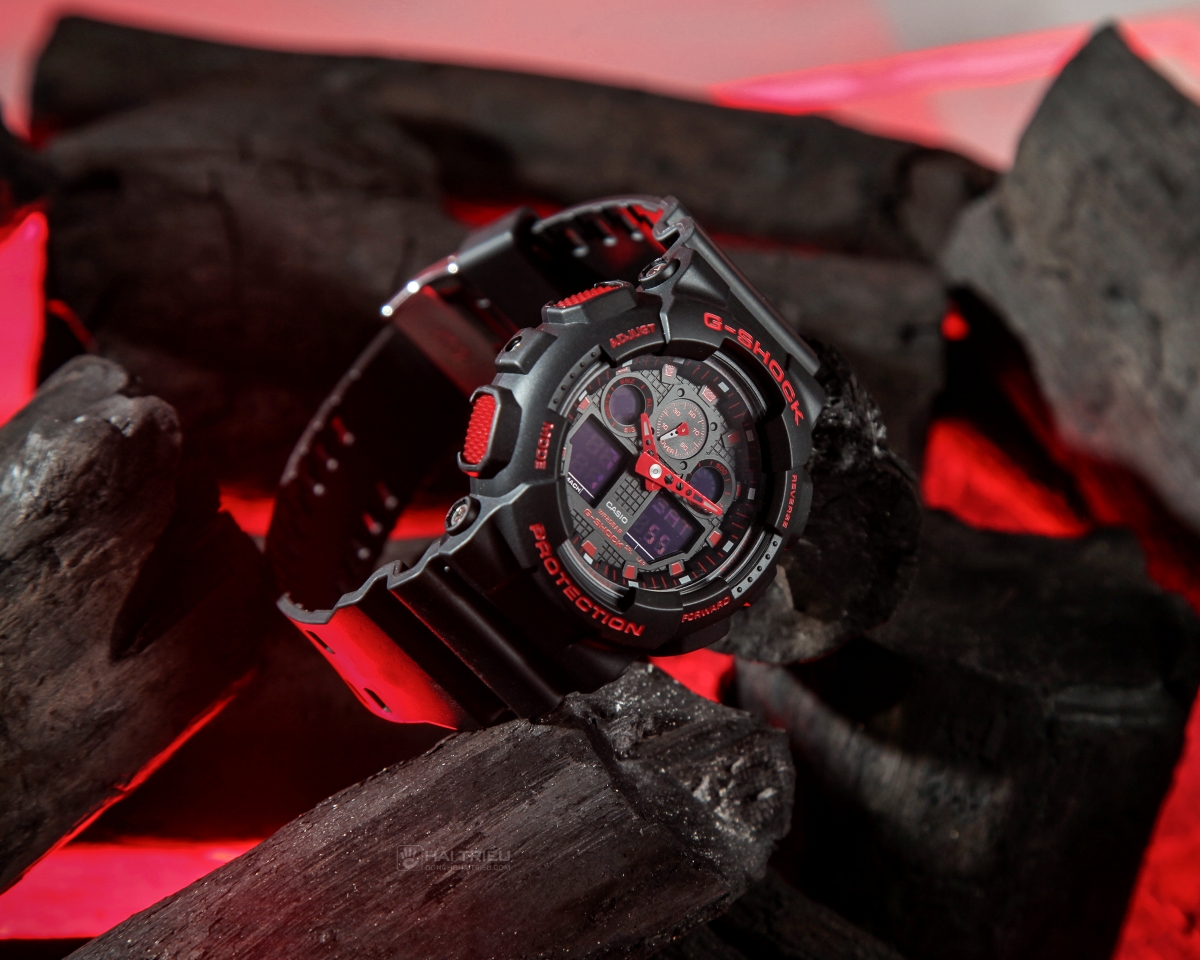 Đồng hồ GA-100BNR-1ADR đen đỏ đặt trên than với ánh sáng đỏ mạnh mẽ và khỏe khoắn.