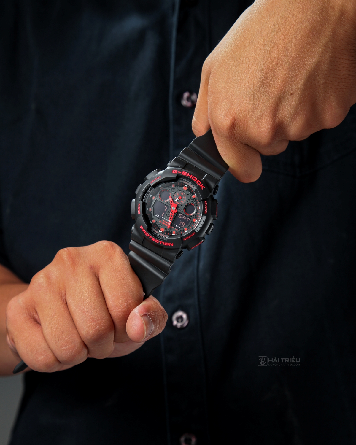 Người dùng cầm đồng hồ G-Shock GA-100 đen đỏ trên tay.