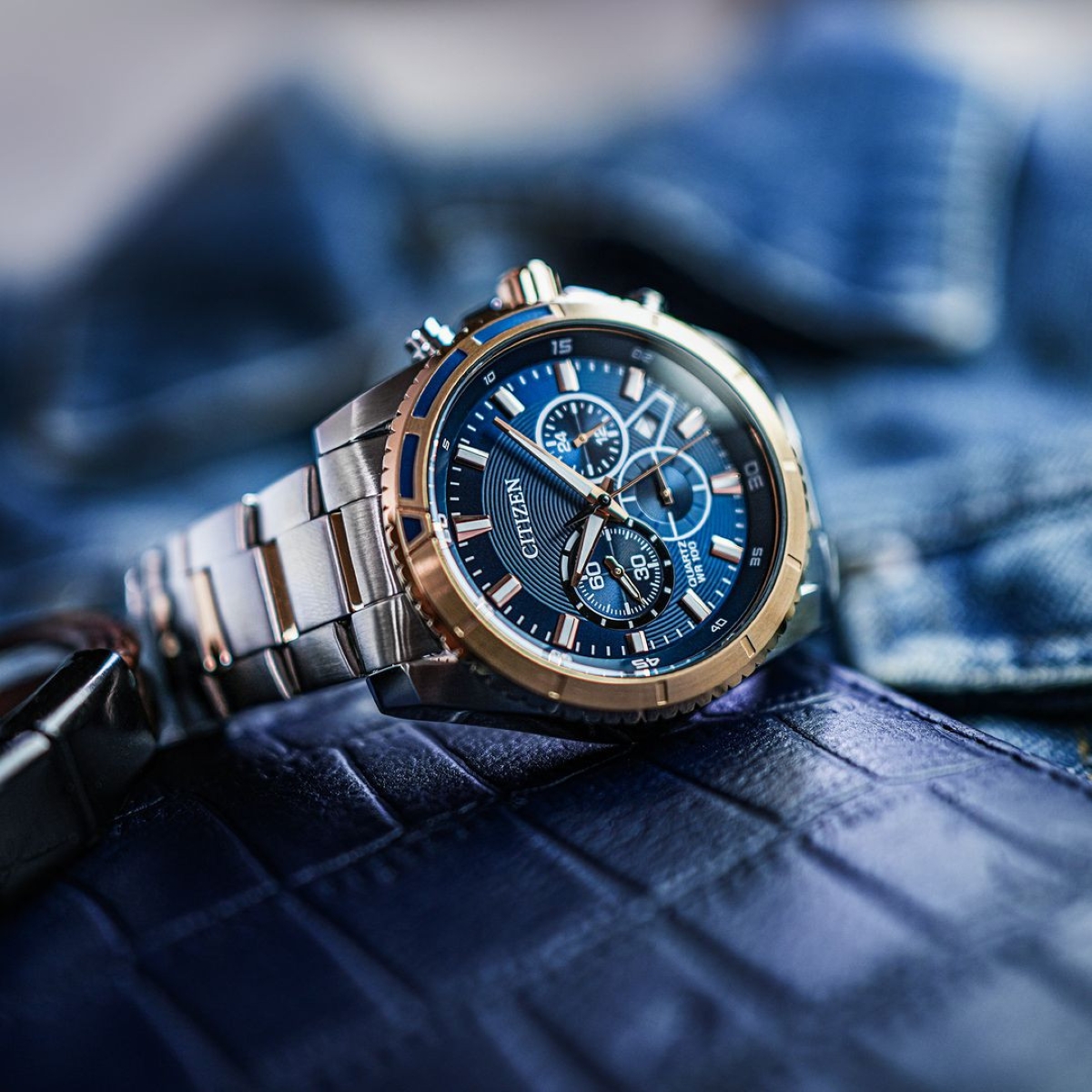 Citizen AN8206-53L nổi bật với sự kết hợp màu sắc phá cách giữa mặt số xanh dương họa tiết vòng tròn đồng tâm và các chi tiết kim, cọc số màu vàng hồng.