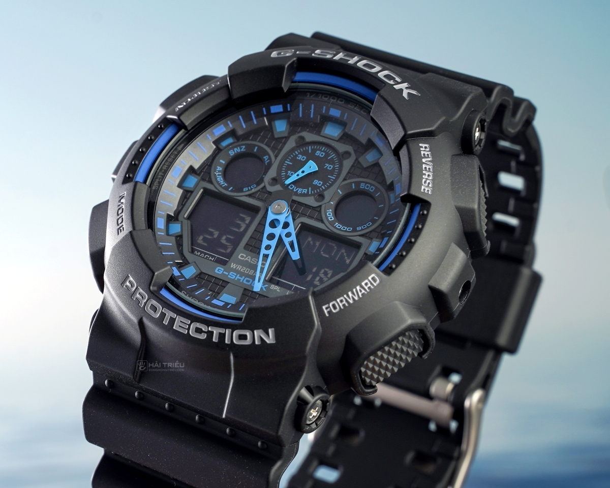 Cận cảnh đồng hồ G-Shock GA-100 phối xanh với vỏ đen và mặt số kim điện tử.
