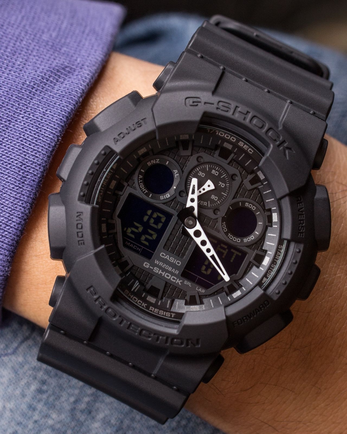 Đồng hồ G-Shock GA-100 all-black đeo trên cổ tay với mặt số lớn.
