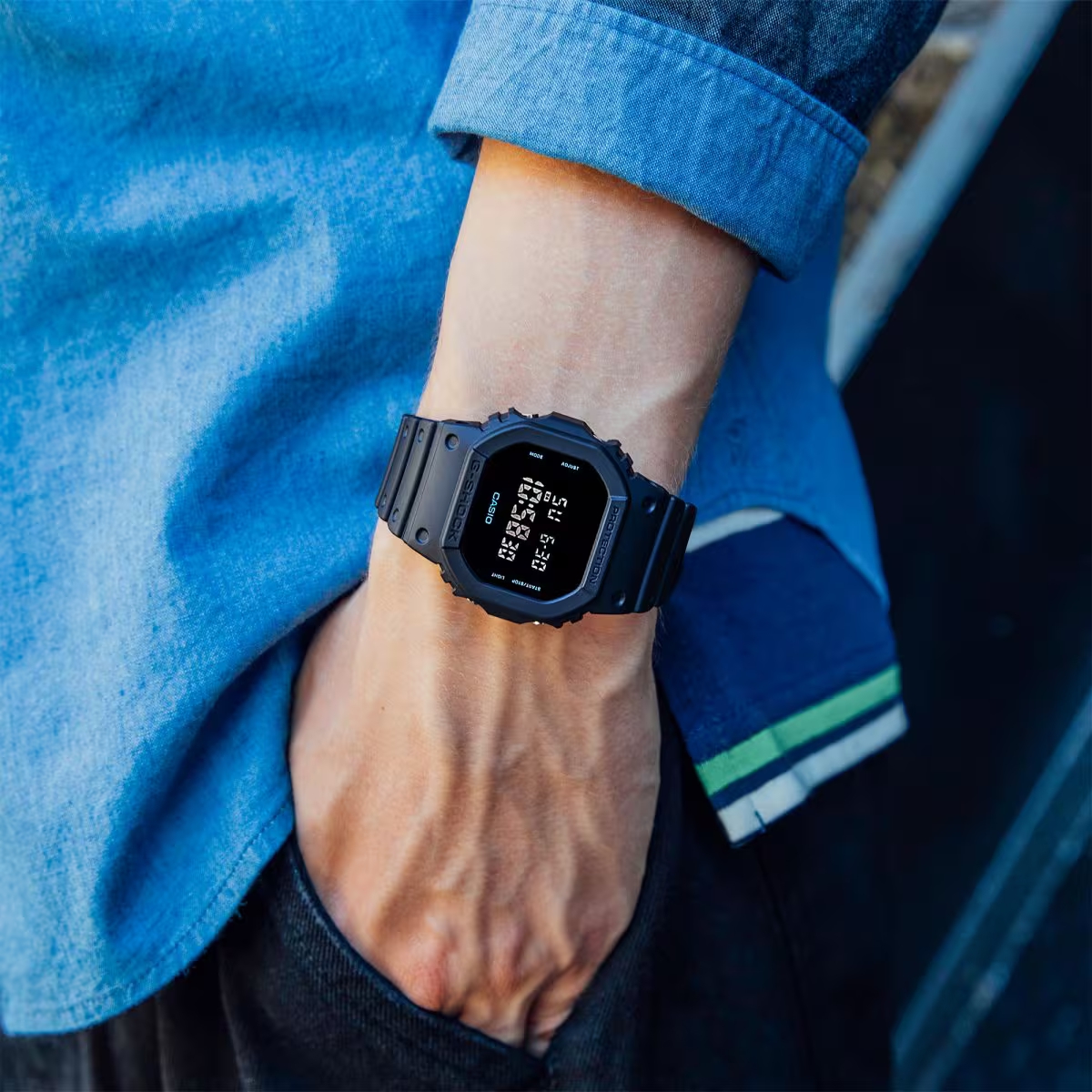 Đồng hồ G-Shock DW-5600 màu đen đeo trên cổ tay, thiết kế mặt vuông cá tính và phù hợp phong cách streetwear.