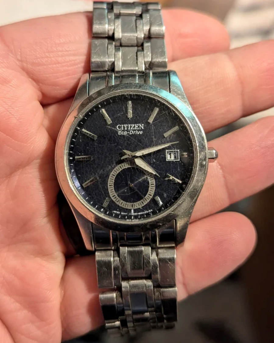 Chiếc đồng hồ Citizen Eco-Drive bị trầy xước chằng chịt trên mặt kính và dây đeo kim loại sau thời gian dài sử dụng.