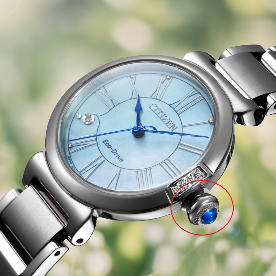 Cận cảnh chi tiết núm vặn đính đá xanh Cabochon Crown được chế tác bo tròn mềm mại trên chiếc đồng hồ nữ Citizen L EM1060-87N.