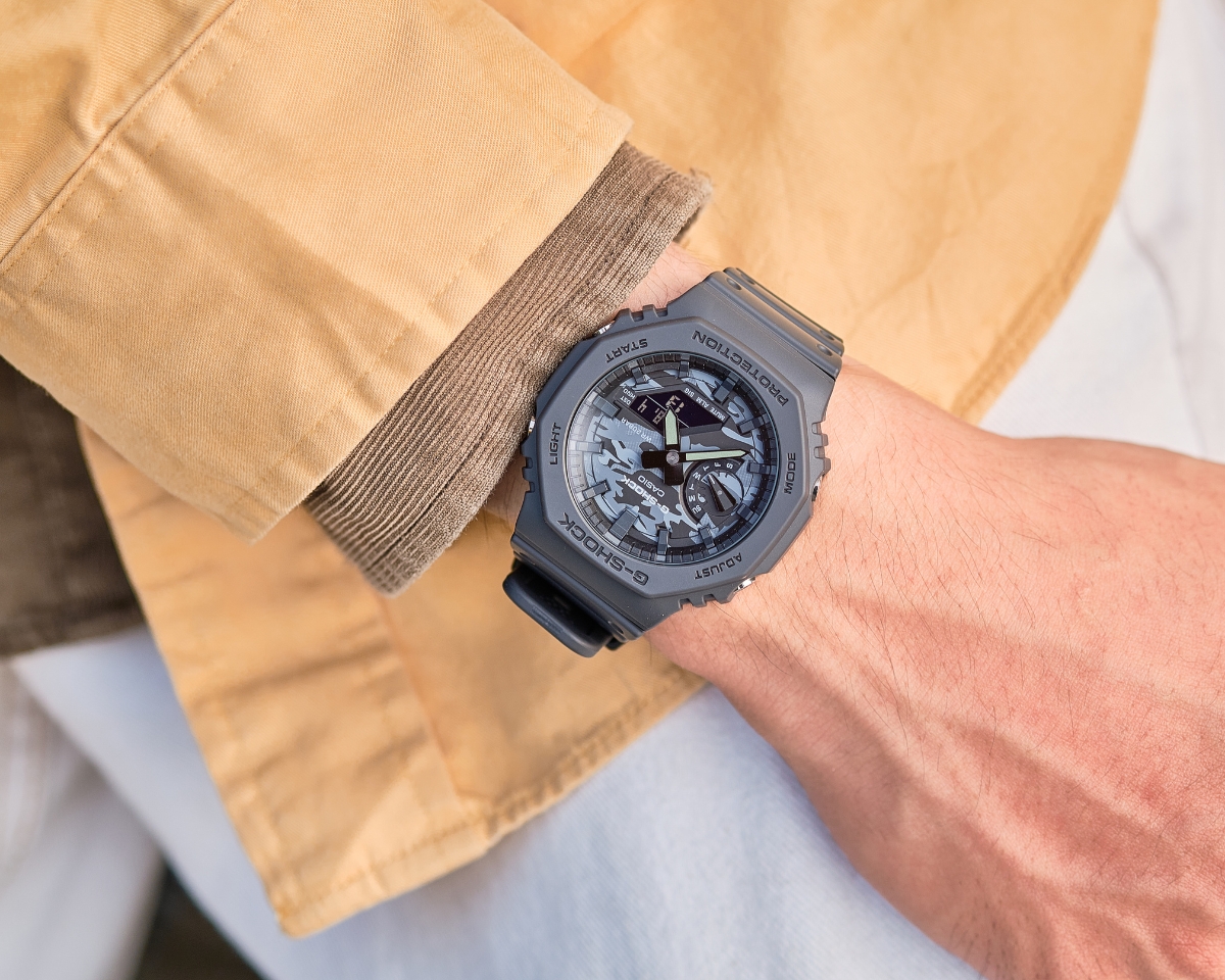 Đồng hồ G-Shock GA-2100 màu xám đeo trên cổ tay cùng trang phục casual.
