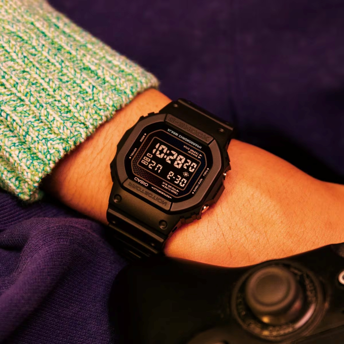 Đồng hồ G-Shock DW-5600 điện tử mặt vuông màu đen đeo trên cổ tay.