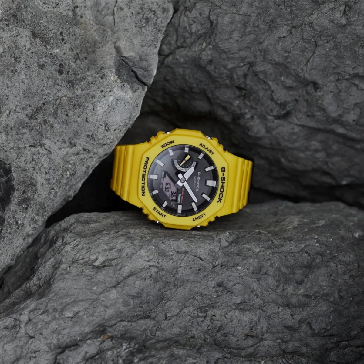 Đồng hồ G-Shock GA-B2100C-9 màu vàng đặt trong hốc đá, nổi bật với phong cách thể thao cá tính.