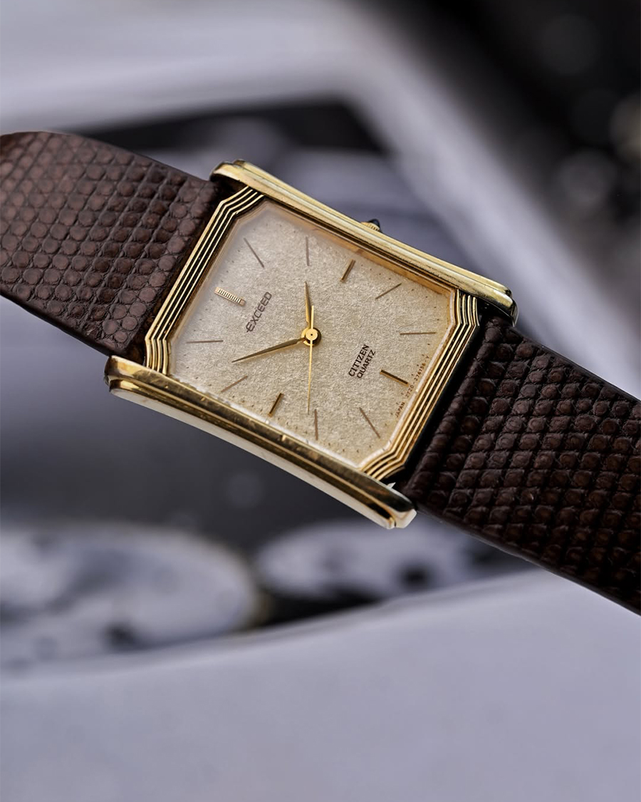Đồng hồ Citizen Exceed Tank vintage vỏ chữ nhật mạ vàng, nổi bật với mặt số vân nhám cổ điển và cọc số thanh mảnh kết hợp dây da nâu.