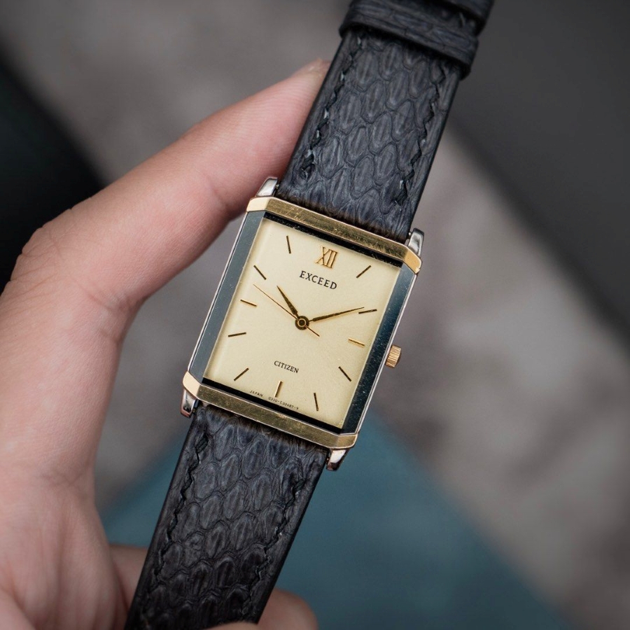 Cầm trên tay chiếc đồng hồ Citizen Exceed Tank vintage, nổi bật với vỏ chữ nhật mạ vàng.