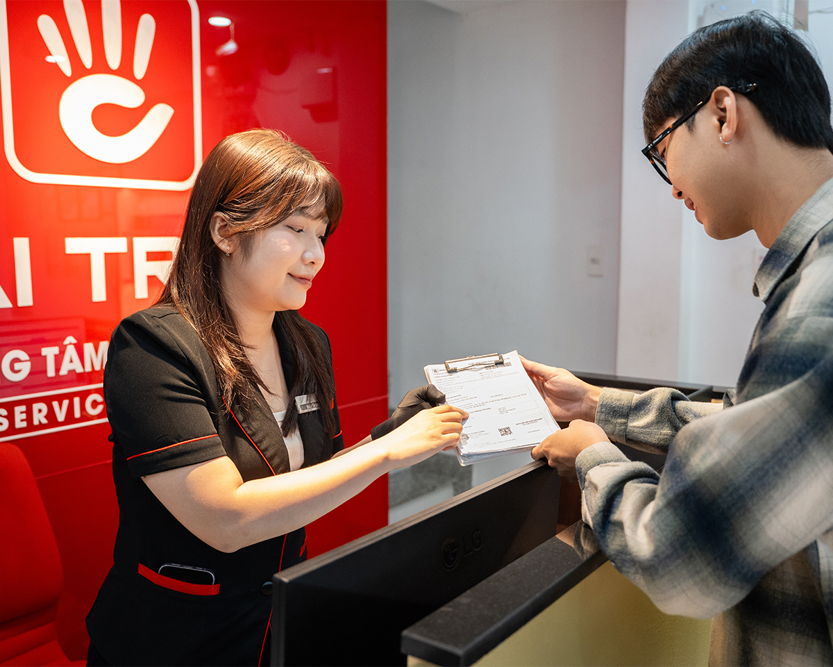 Nữ nhân viên đang hướng dẫn cho một khách hàng nam tại quầy lễ tân của Trung tâm Bảo dưỡng Đồng hồ Hải Triều.