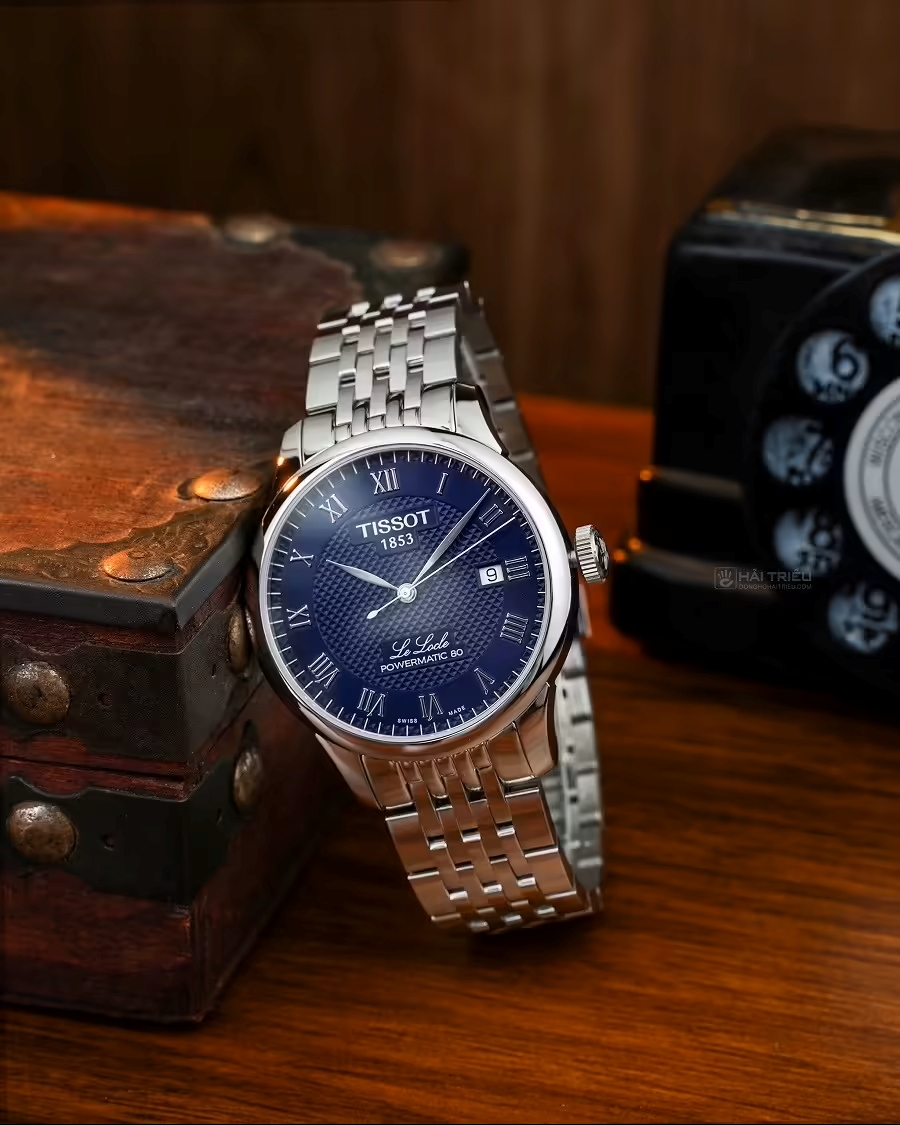 Tissot Le Locle với mặt số guilloché, chữ số La Mã và kim dauphine, phù hợp phong cách công sở lịch sự.